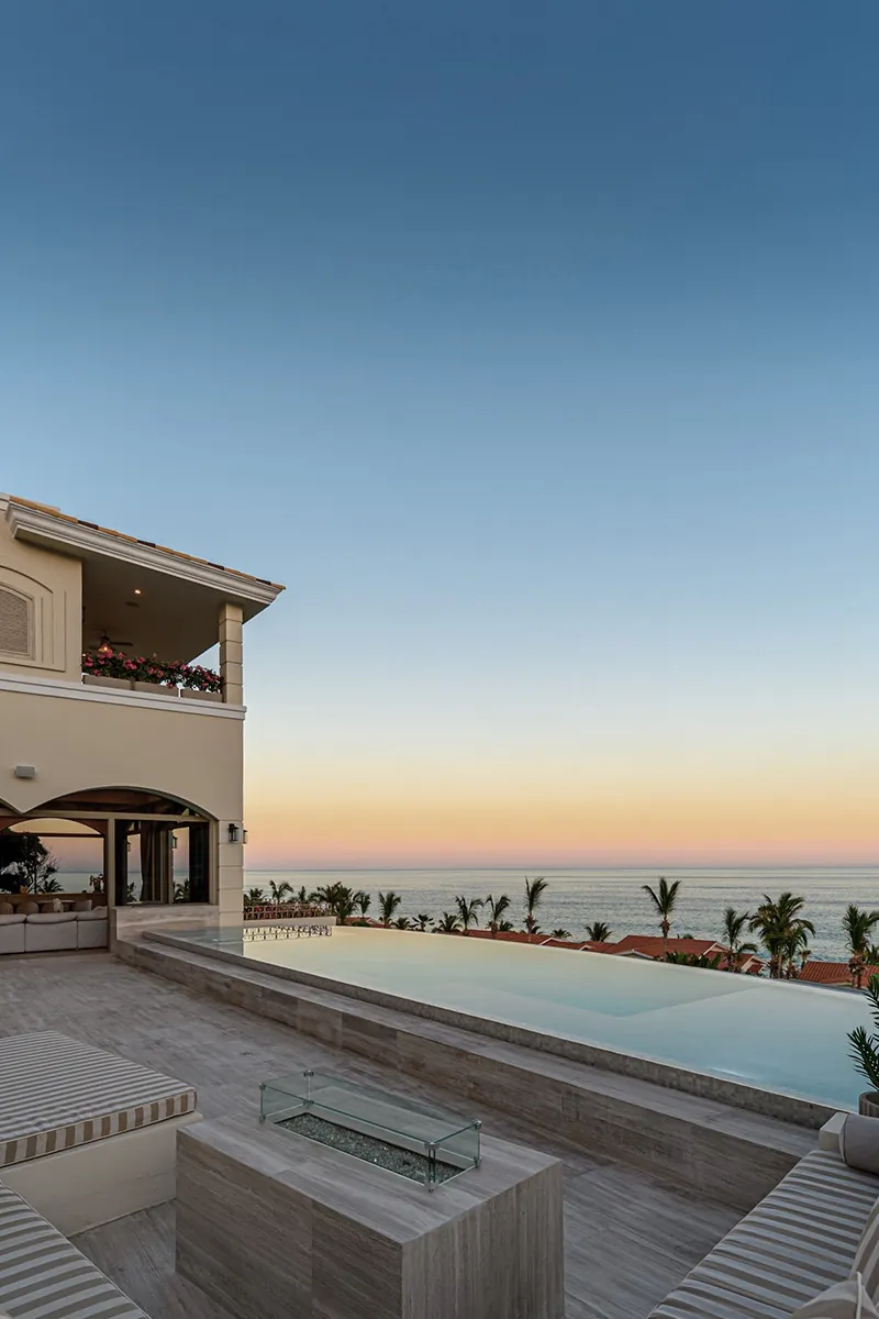 The terrace and infinity pool at dusk, uncluttered, with service kept out of view.