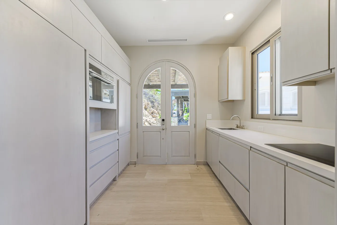 Butler's pantry in soft white with a glazed arched door opening to the garden.