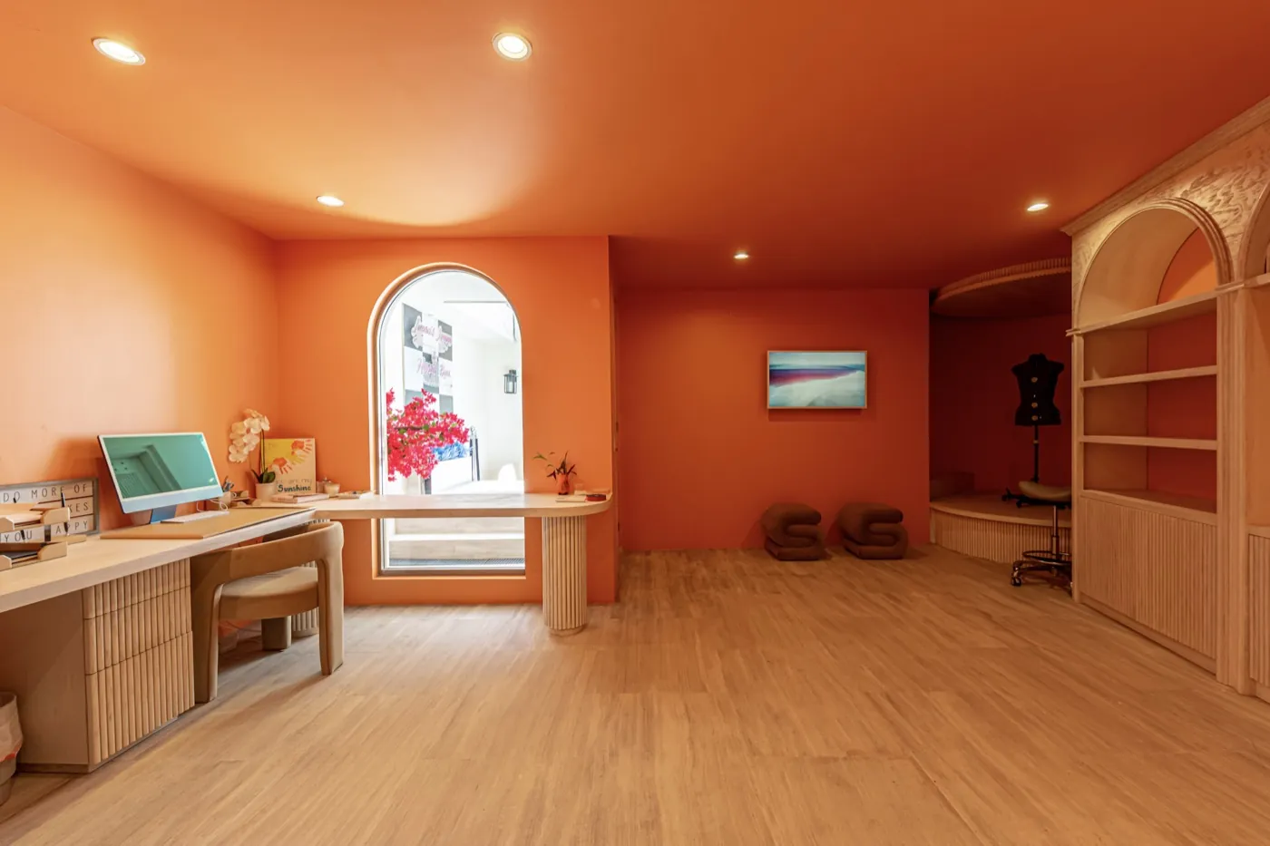 Terracotta-toned studio with a pale timber desk, arched window and light oak flooring.