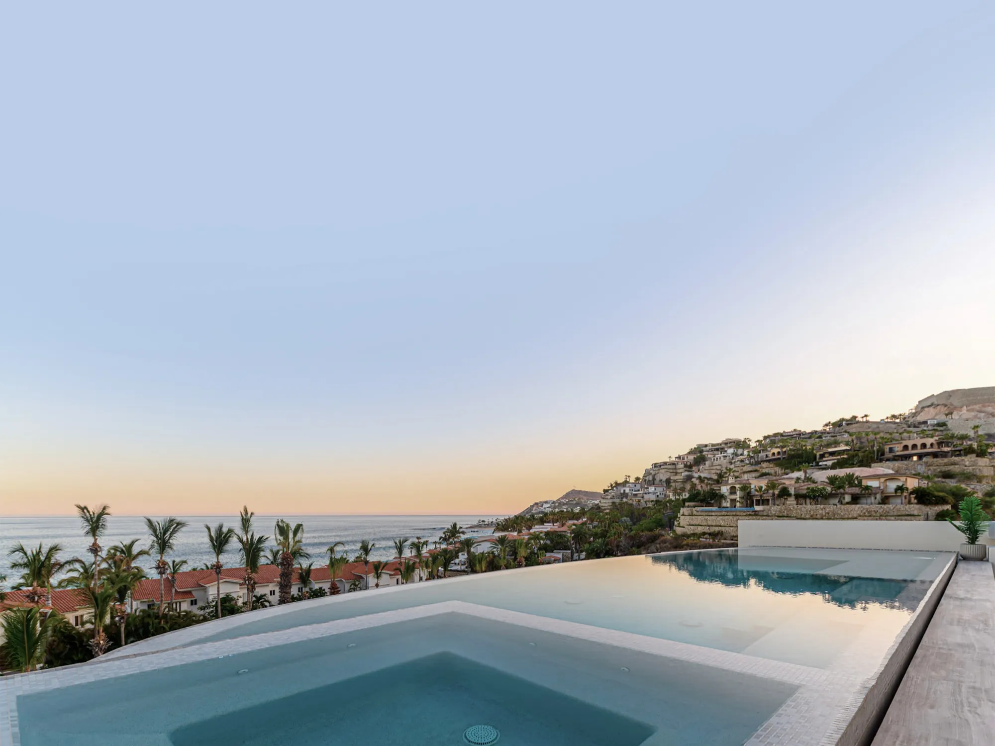 The villa's infinity pool and terrace above the Los Cabos coast at dusk.
